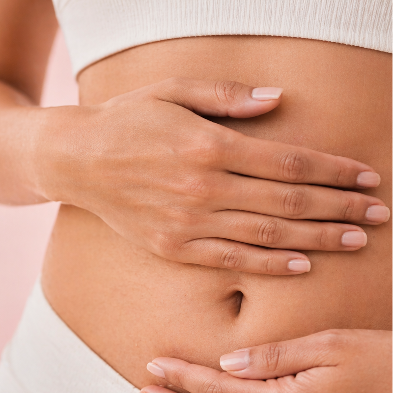 Close-up of a person's hands on their stomach against a light background